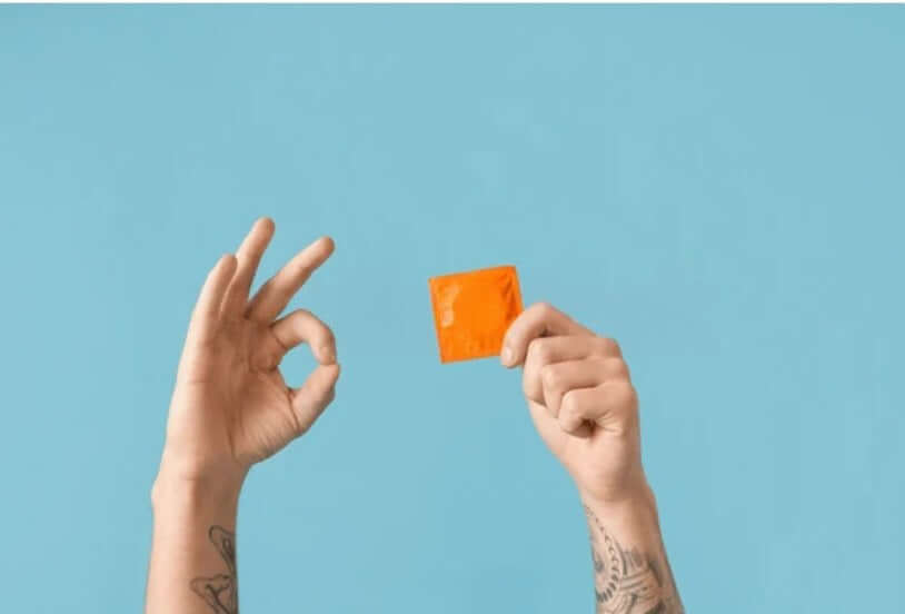 10 Reasons must Use Condoms shown with hands holding an orange condom against a blue background.
