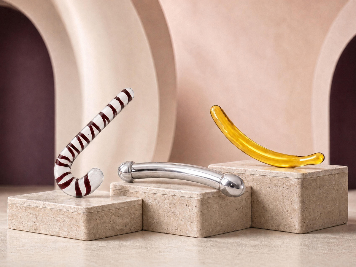 Three curved dildos in glass and stainless steel displayed on stone pedestals