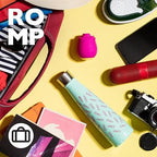 Flat lay of a stylish bag, water bottle, camera, and various accessories on a yellow background with the ROMP logo.