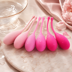 Pink progressive Kegel balls arranged on soft satin surface