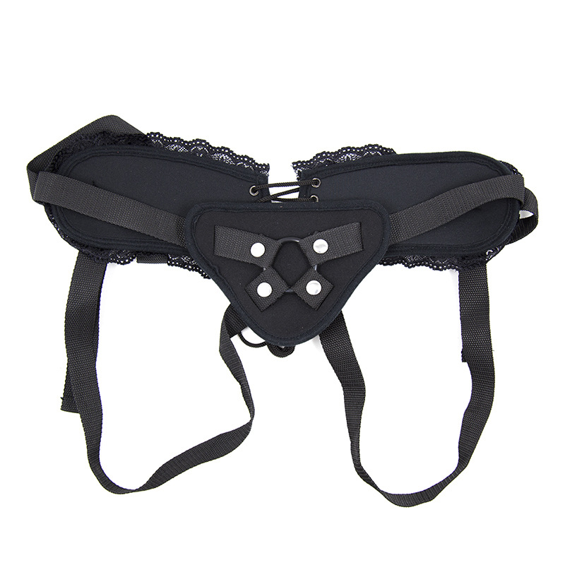 Black adjustable lace-trim strap-on harness laid flat with adjustable straps and front ring holder