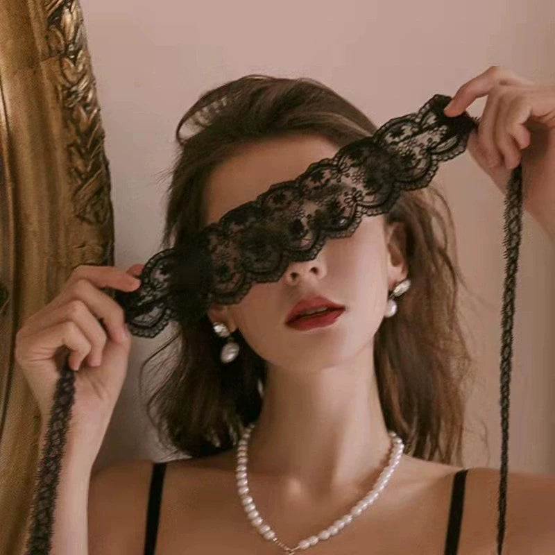 Model holding a black floral lace tie-on blindfold over her eyes