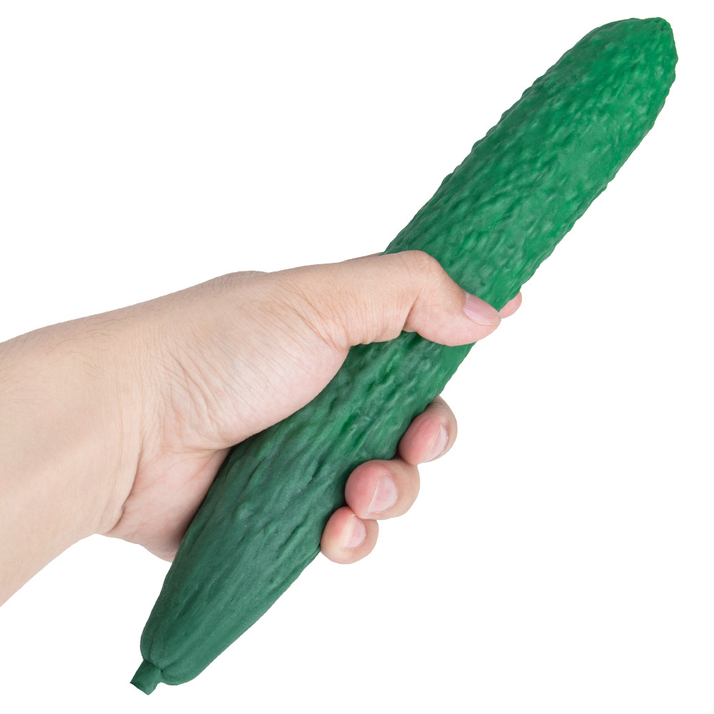Hand holding long green textured cucumber-shaped silicone dildo for scale