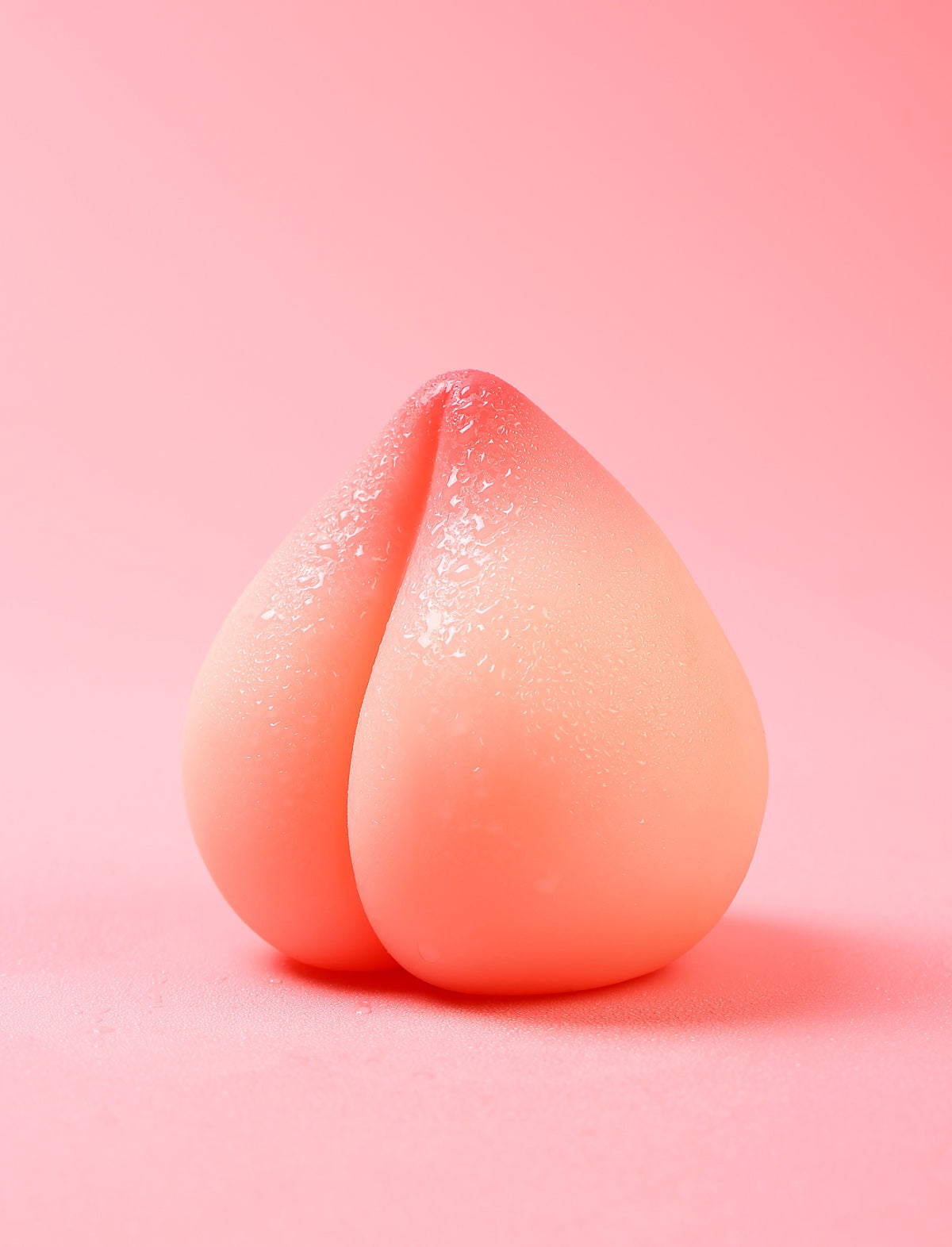 Peach-shaped TPE male masturbator on pink background