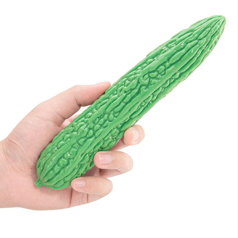 Hand holding the green bitter melon silicone dildo for scale