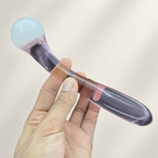 Curved pink glass dildo shown in hand for scale