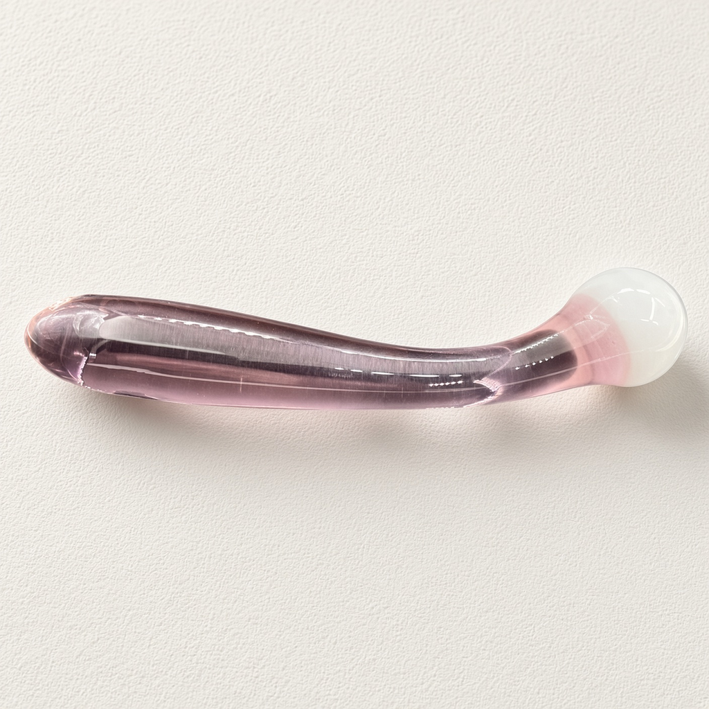 Curved pink glass dildo with rounded white ball head on a light background