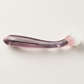 Curved pink glass dildo with rounded white ball head on a light background
