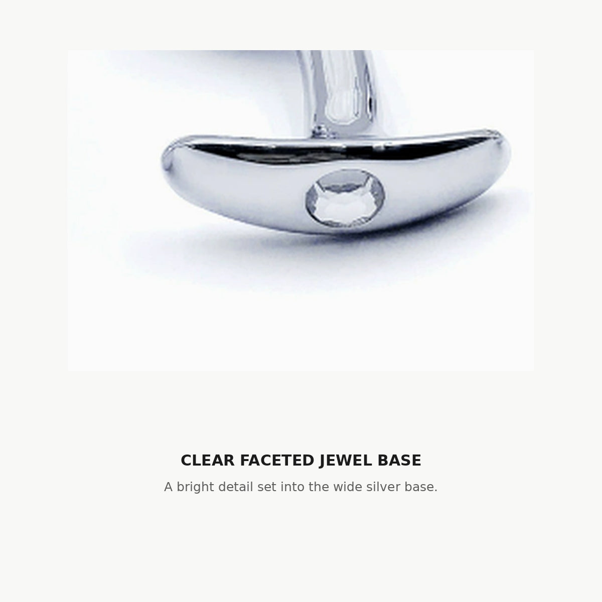 Close-up of the clear faceted jewel set into the wide silver base of the curved aluminum anal plug