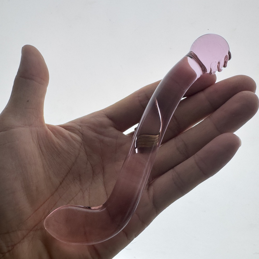 Hand-held scale view of curved double-ended purple glass dildo
